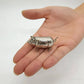 Mini antique pig tape measure shown in the palm of a hand