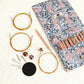Floral knitting needle pouch with rose gold tips, cables, connectors and accessories in a flat lay