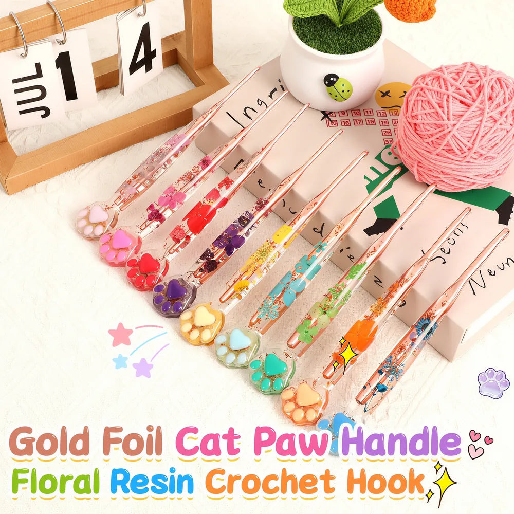 Nine rose-gold-tone crochet hooks with floral resin handles and colorful cat paw ends