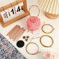 Rose gold circular knitting needle set displayed with pink yarn and floral pouch