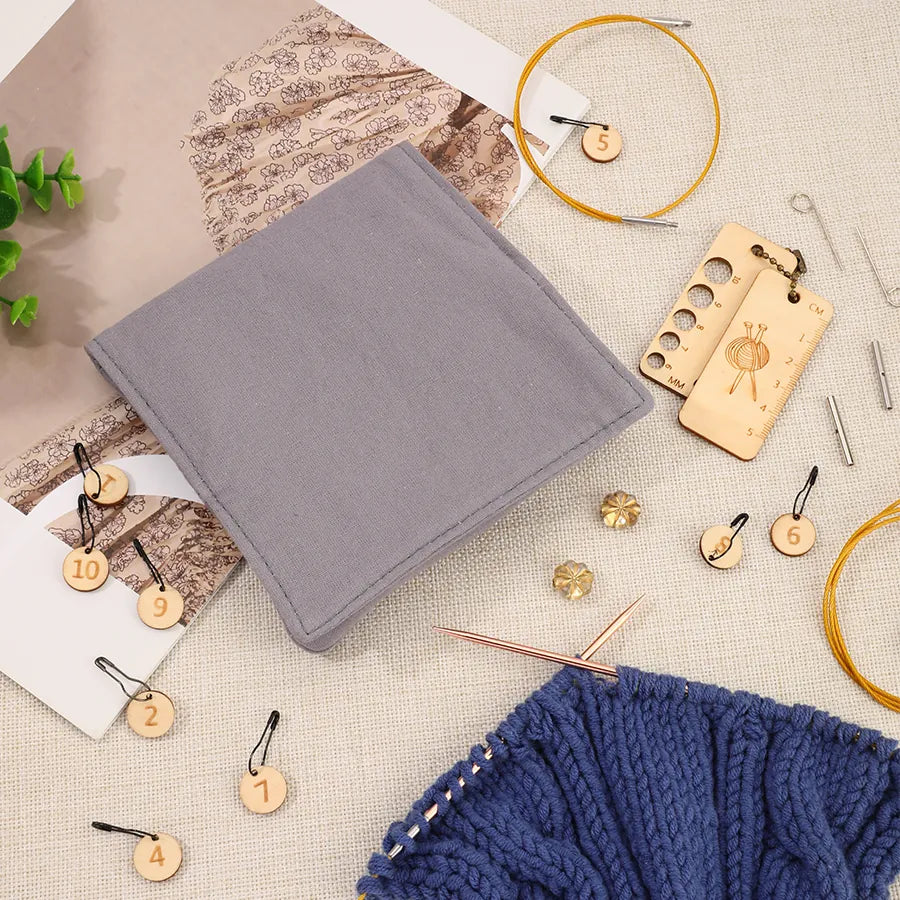 Closed gray knitting needle organizer beside cables and knitting accessories