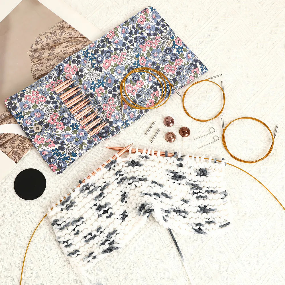 Rose gold circular knitting needles used on a black and white knitting project