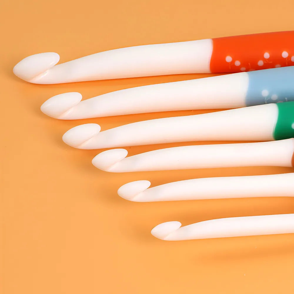 Close-up of six smooth white crochet hook heads in graduated sizes